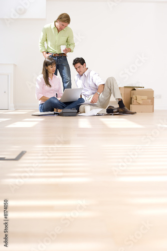 Photo: Man and colleague looking at woman's laptop computer by boxes Man and colleague looking at woman's laptop computer by boxes