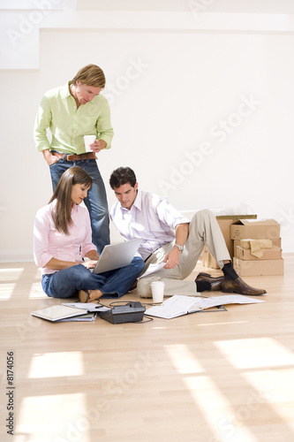 Photo: Man and colleague looking at woman's laptop computer by boxes Man and colleague looking at woman's laptop computer by boxes