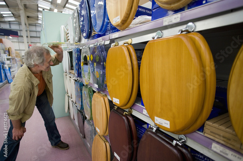 Photo: Senior man looking at toilet seats in shop Senior man looking at toilet seats in shop