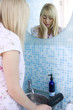 Young woman at mirror in bathroom