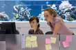 Woman and colleague at workstation, fish tank in background