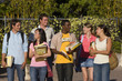 Students with books outdoors, smiling