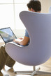 Man with laptop computer in armchair, rear view