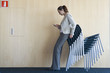 Woman checking text messages while leaning on stack of chairs