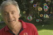 A senior adult playing with bubbles.