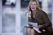 Businesswoman with suitcase talking on cell phone