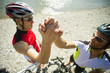Two male cyclists shake hands.