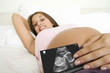 Pregnant woman displaying sonogram image