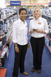 Young saleswoman with colleague in shop, smiling, portrait