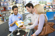Photo: Young couple with saleswoman, looking at camera, smiling, side view Young couple with saleswoman, looking at camera, smiling, side view