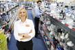Young saleswoman in electronics aisle with arms crossed, smiling, porttrait
