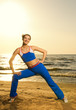 Beautiful young woman doing fitness exercise on a beach