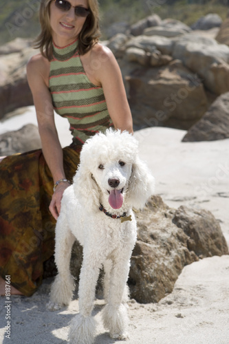 Photo: Woman on rock with dog on beach, smiling Woman on rock with dog on beach, smiling