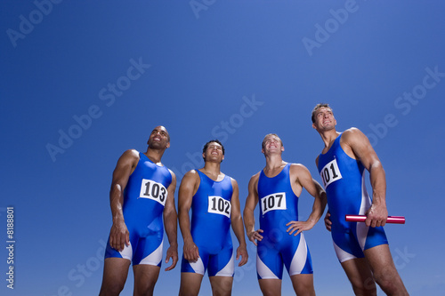 Photo: Male athletes in row, smiling, low angle view Male athletes in row, smiling, low angle view