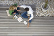 Photo: Couple sitting on patio decking, eating sushi with chopsticks, overhead view Couple sitting on patio decking, eating sushi with chopsticks, overhead view