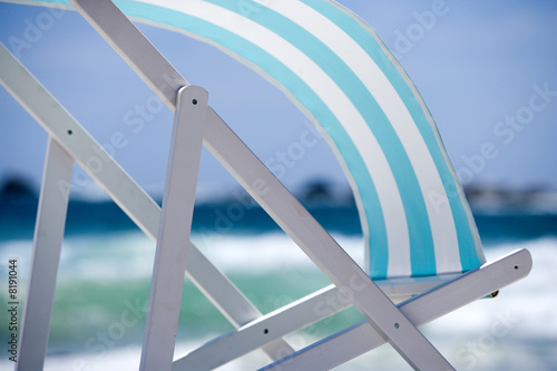 Photo: Striped turquoise deckchair blowing in wind on beach, side view, mid-section Striped turquoise deckchair blowing in wind on beach, side view, mid-section