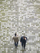 Two businessmen walking across a place and talking on the cellphone.