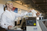 Photo: Businessman standing at check-in counter, passing ticket to female attendant, smiling, side view Businessman standing at check-in counter, passing ticket to female attendant, smiling, side view