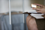 Photo: Businesswoman with folder in lap, holding personal electronic organiser, side view, mid-section Businesswoman with folder in lap, holding personal electronic organiser, side view, mid-section