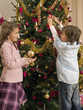 Siblings decorating a Christmas tree.
