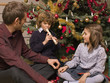 Boy playing a flute for his sister and father.
