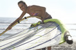 Photo: Young woman in bikini assembling windsurfer on sandy beach, smiling, side view, portrait Young woman in bikini assembling windsurfer on sandy beach, smiling, side view, portrait