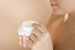 Woman holding a pot of moisturising cream