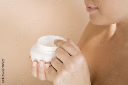 Photo: Woman holding a pot of moisturising cream Woman holding a pot of moisturising cream