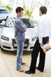 A young man talking to a car salesman