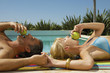 Couple lying down beside the pool.