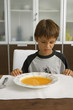 Boy sitting with a bowl of soup.