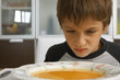 Boy sitting with a bowl of soup.
