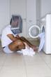 Man sitting in front of washing machine with a basket on his head