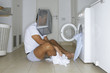 Man sitting in front of washing machine with a basket on his head