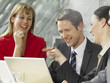 Two businesswomen and a businessman smiling in a meeting