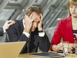 Photo: Close-up of a businessman holding his head with a businesswoman sitting beside him Close-up of a businessman holding his head with a businesswoman sitting beside him