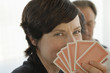Woman holding playing cards close to her face