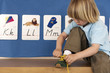 Photo: Blonde boy (4-6) sitting on bench in classroom, tying shoelace, alphabet cards on wall Blonde boy (4-6) sitting on bench in classroom, tying shoelace, alphabet cards on wall
