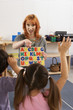 Photo: Children (4-6) learning the alphabet in classroom, hands raised, focus on teacher in background Children (4-6) learning the alphabet in classroom, hands raised, focus on teacher in background