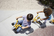 Photo: Boy and girl (4-6) riding toy tricycle and push scooter in playground, overhead view (tilt) Boy and girl (4-6) riding toy tricycle and push scooter in playground, overhead view (tilt)