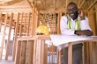Photo: Businessman with blueprints using mobile phone in partially built house, smiling, portrait Businessman with blueprints using mobile phone in partially built house, smiling, portrait