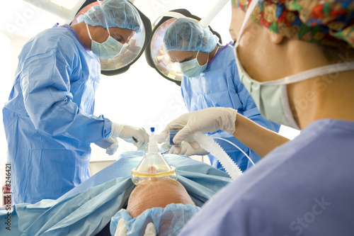 Photo: Surgeons attending to patient on bed in operating room Surgeons attending to patient on bed in operating room