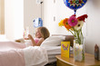 Girl (8-10) in hospital bed reading card, side view