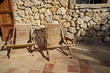 Two wooden deckchairs on tiled patio, stone wall in background