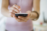 Photo: Woman using personal electronic organiser, mid-section, front view, close-up, focus on foreground Woman using personal electronic organiser, mid-section, front view, close-up, focus on foreground