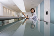 Photo: Businesswoman reading financial newspaper in lobby, reflection on long glass table, smiling, side view, portrait Businesswoman reading financial newspaper in lobby, reflection on long glass table, smiling, side view, portrait