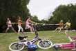 Photo: Group of children (7-9) playing tug-of-war in park near bicycles, boys versus girls, side view Group of children (7-9) playing tug-of-war in park near bicycles, boys versus girls, side view
