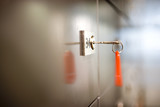 Photo: Key on red key ring hanging from lock on door, side view, close-up (differential focus) Key on red key ring hanging from lock on door, side view, close-up (differential focus)