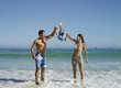 Photo: Parents swinging son (5-7) up into air, standing in surf on beach, smiling, front view Parents swinging son (5-7) up into air, standing in surf on beach, smiling, front view