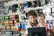 Photo: Young couple looking at visual screen beside bike accessories display rack in bicycle shop, smiling Young couple looking at visual screen beside bike accessories display rack in bicycle shop, smiling